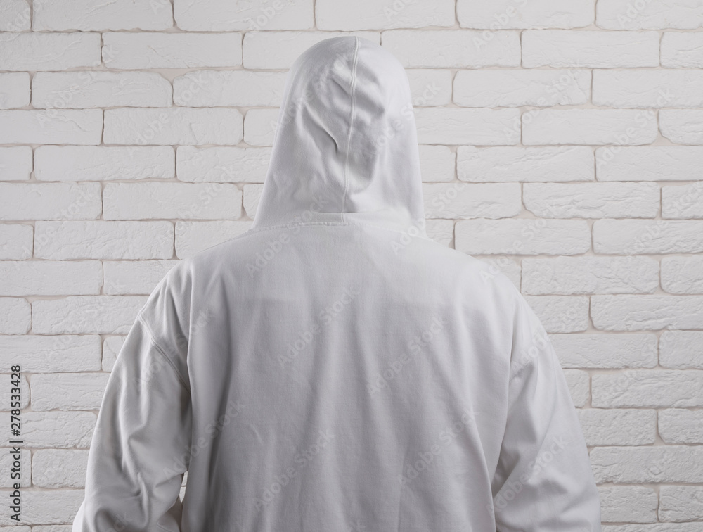 Poster man in a white hood from the back, white brick wall background