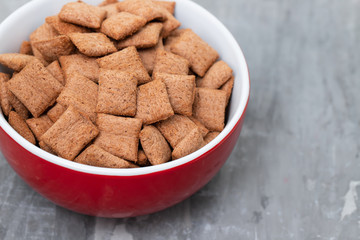 Chocolate pillows in red bowl on ceramic background