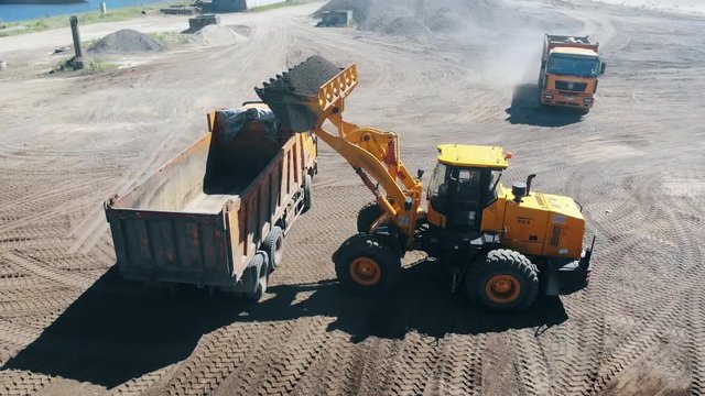 Construction site with rubble getting relocated by vehicles. Mining equipment at quarry.