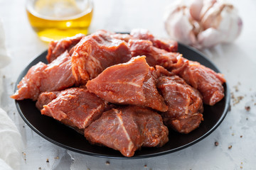 raw pork in marinate on black plate on ceramic background