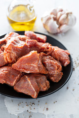 raw pork in marinate on black plate on ceramic background