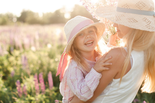 laughing girl in mom's hands at sunset in the middle of a field