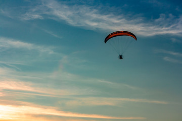 A powered paraglider pilot in flight at sunset background - 278534027