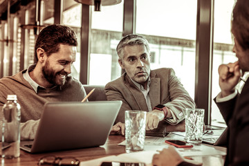 Positive delighted brunette man working at computer