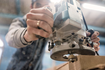 Carpenter using electric woodworking. Routing is a high speed process of cutting, trimming, and shaping wood