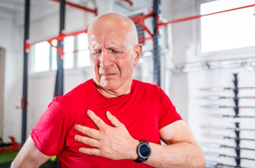Senior man at the gym suffering from pain in shoulder