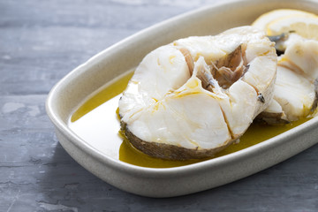 boiled fish with olive oil in dish on ceramic background