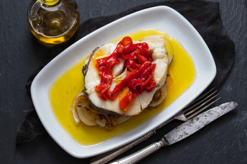 boiled fish with vegetables, olive oil in dish on ceramic background