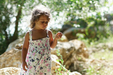 A blond girl of three years thoughtful near the Acheron River with its pristine nature in Epirus