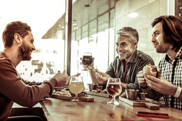 Joyful males spending time together in cafe