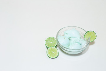 Lime ice cream with green lime slices on white background with copy space – Citrus flavored frozen sweet desert – Healthy natural homemade cold snack