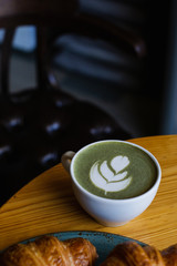 match Latte with beautiful latte art and croissant on dark background on the table. Perfect breacfast in the morning.