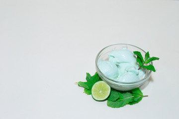 Lime and mint ice cream with lime slices and mint leaves on white background with copy scape – Healthy green cold sorbet – Sweet and tasty frozen desert