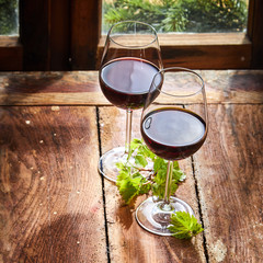 Two glasses of red wine with green vine leaves