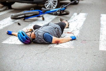 Scene of a road accident with injured cyclist lying on the pedestrian crossing near the broken...