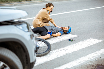 Road accident with injured cyclist lying on the pedestrian crossing near the broken bicycle,...