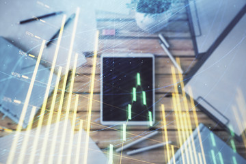 Obraz premium Double exposure of forex graph on digital tablet laying on table background. Concept of market analysis