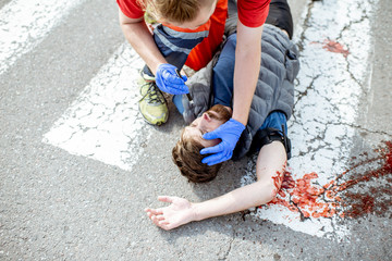 Medic checking unconscious person with flashlight, applying first aid to the bleeding person on the...
