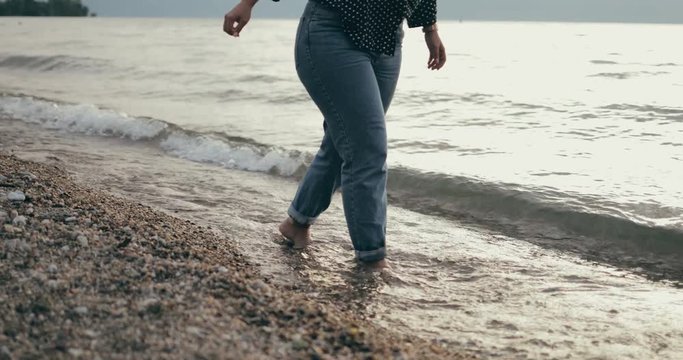 Woman's legs while walking at the beach in jeans 4k