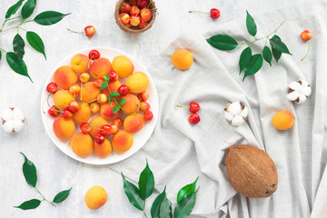 Summer fruits, apricot, coconut, cherry on grey background, flat lay, top view