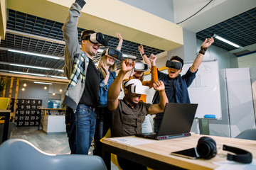 Supportive group of young diverse multiracial business people wearing vr goggles celebrating their victory in creative modern loft office