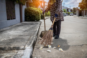 Worker sweeping the pavement with broom. Street sweeper cleaning road in the village