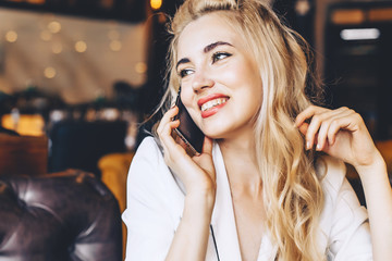 Beautiful happy smiling woman talking on the phone in a cafe