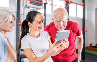 Personal trainer showing results of training on tablet to senior couple