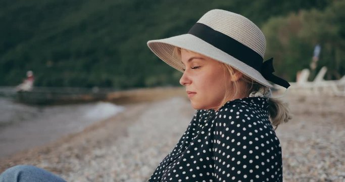 Young woman sitting on the beach looking at sunset 4k