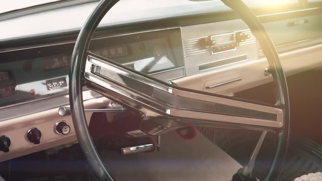 Classic retro or vintage car interior with steering wheel in sunset light, close up