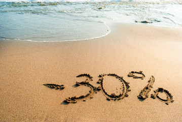 inscription on the sand minus thirty percent, 30 %, sea wave on the sand with the inscription thirty