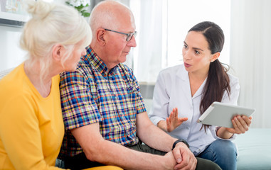 Nurse gives treatment advices to senior couple at home
