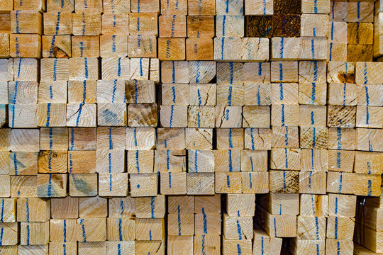 Stacked wooden bars fence on a lumber yard. Building materials.