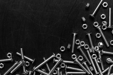 Top view of stainless steel bolts or iron nails with silver color on empty rubbed out on blackboard chalkboard texture background. Metal screws for use in sheet metal.