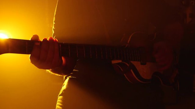 Man sat playing guitar in warm lighting