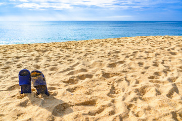 Blue andals on the sand tropical beach with ocean wave, island, white fluffy clouds blue sky and ripple of water splash from emerald blue-green sea water during summer vacation. 