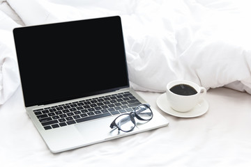 Fototapeta premium The laptop and alarm clock in the morning on a white bed. copy space. Lifestyle Concept