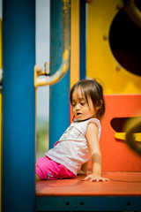 Adorable little 1-2 year old Asian toddler girl having fun on playground.