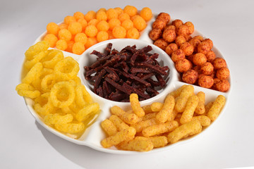 Mix of snacks on a white plate isolated on white.