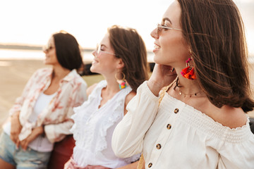 Young three happy pretty women friends posing outdoors near car.