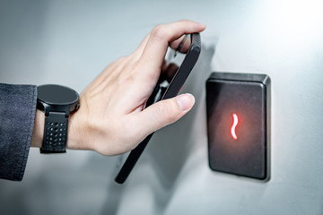 Male hand using smartphone for sensor scanning. Infrared sensor technology for automatic door...