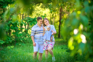 Fototapeta premium Friendly family. parents walk with their little daughter in a beautiful summer park at sunset. people concept.