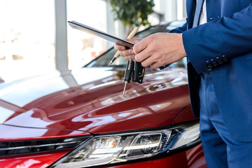 Dealer holding keys from new car close up