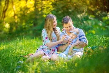 friendly family resting in a beautiful summer park. sit on the blanket and play. people concept.