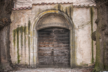 Ancient wooden door in old stone castle wall.