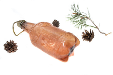 Brown plastic bottle with a sprig of pine and a fir cone on a white background.
