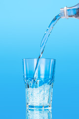 Close up pouring purified fresh drink water from the bottle on table