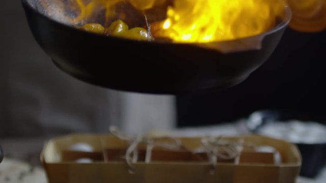 Close up of male hand setting fire on frying vegetables