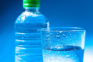 Glass of water with a bottle on table
