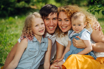 Fototapeta premium Portrait of a family during picnic on grass in the gardens